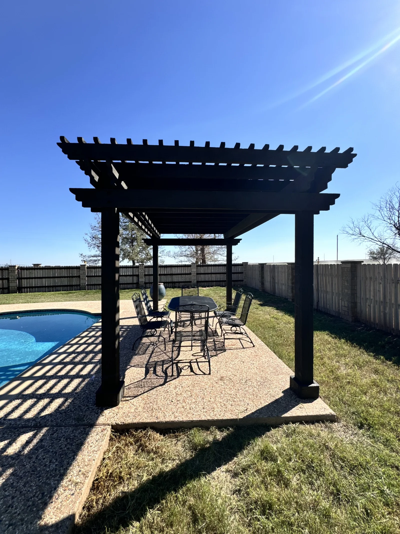 Black pergola beside pool