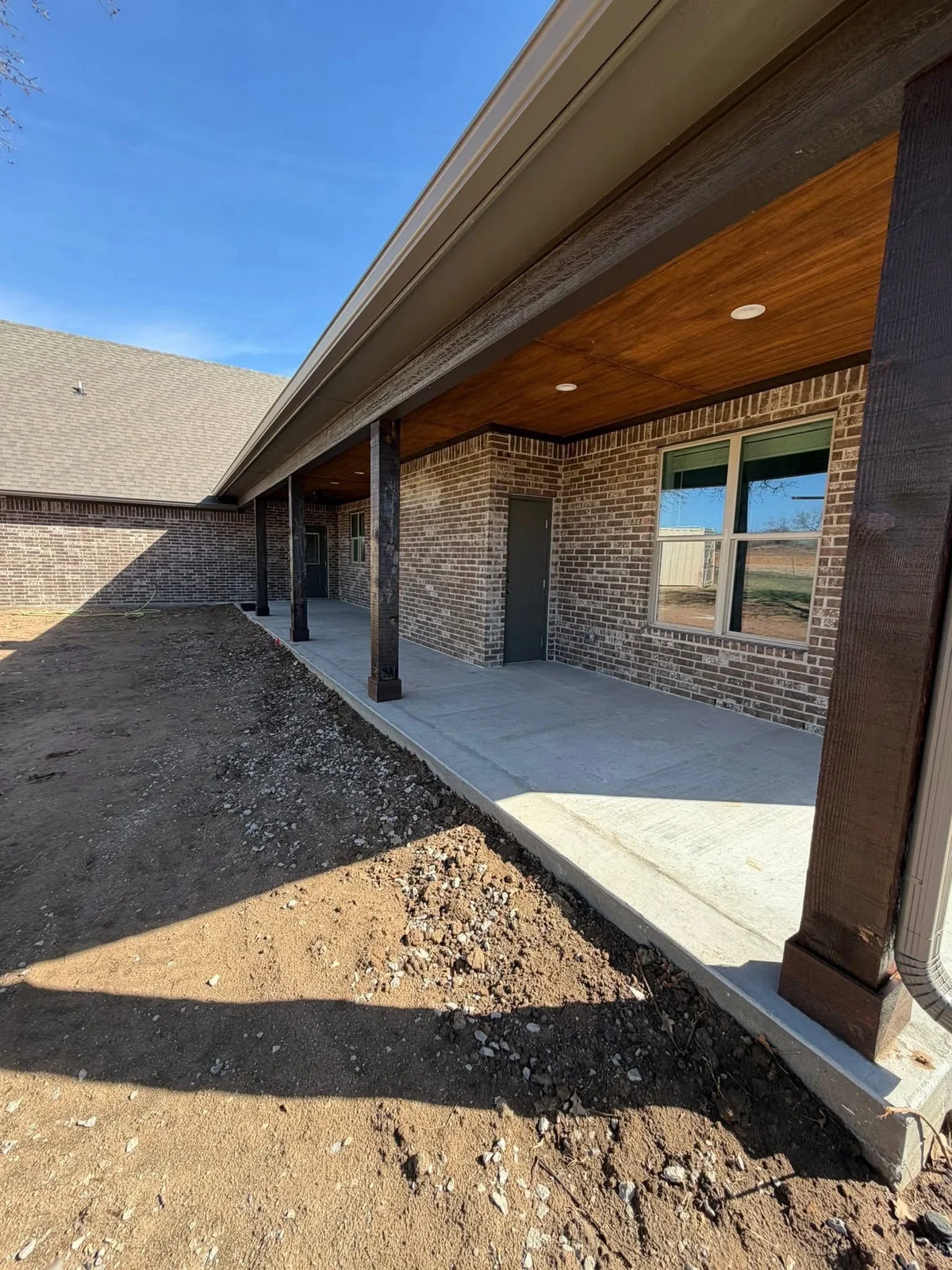 Wood-lined patio ceiling and posts along a brick exterior