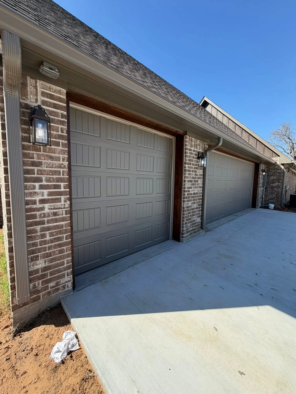 Two gray paneled garage doors framed by brickwork and light trim
