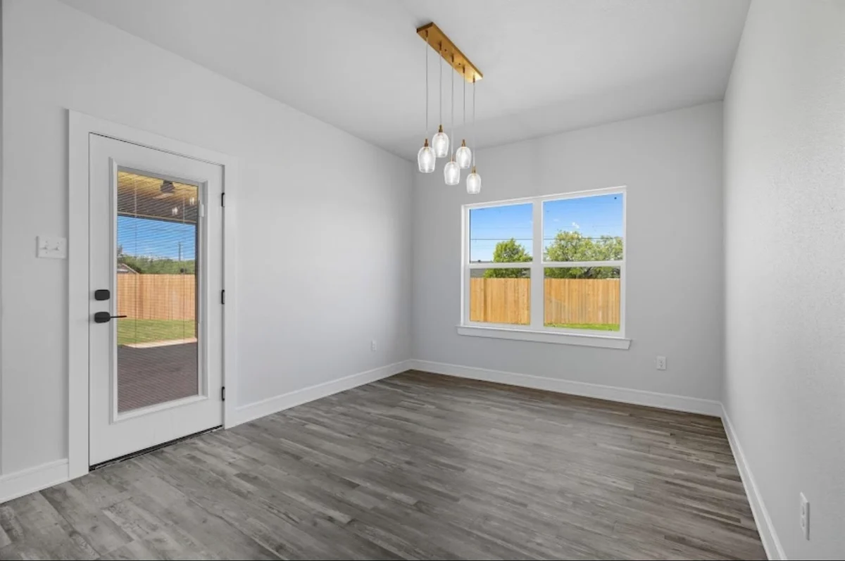 White dining-room walls and trim with a window, glazed door, and pendant lights