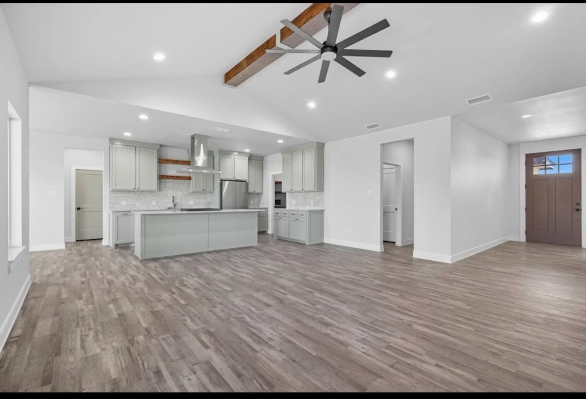 White walls and pale-gray kitchen cabinets beneath a wood ceiling beam and fan