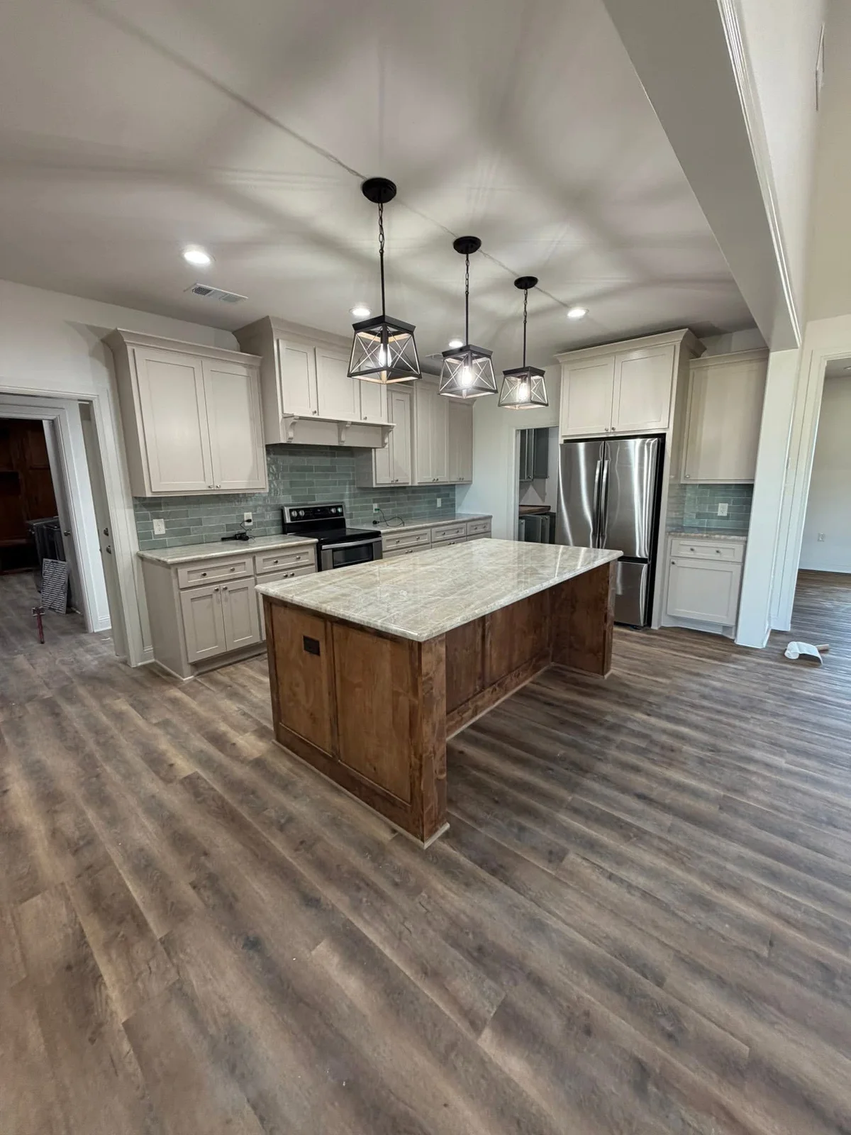 White kitchen cabinets and a wood island beneath three pendant lights